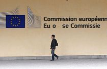 Homem caminha à porta da sede da Comissão Europeia em Bruxelas, segunda-feira, 1 de julho de 2013. 