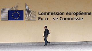 Homem caminha à porta da sede da Comissão Europeia em Bruxelas, segunda-feira, 1 de julho de 2013. 