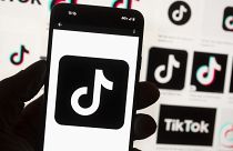 Το λογότυπο του TikTok εμφανίζεται σε ένα κινητό τηλέφωνο μπροστά από μια οθόνη υπολογιστή.