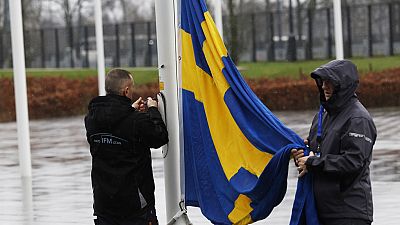 Members of protocol attach the Swedish flag as they prepare for a flag raising ceremony to mark the accession of Sweden at NATO headquarters in Brussels, Monday, March 11, 202