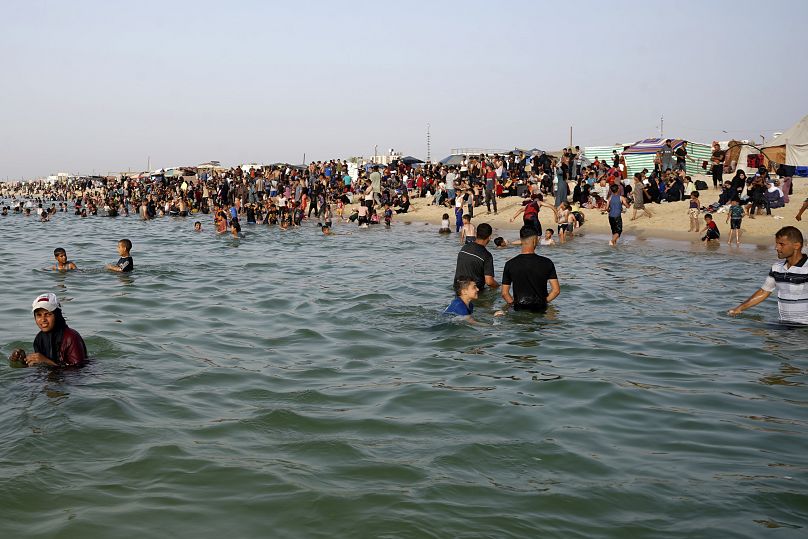 Displaced Palestinians cool off during a heatwave at Khan Younis beach, southern Gaza Strip, 20 May 2024.