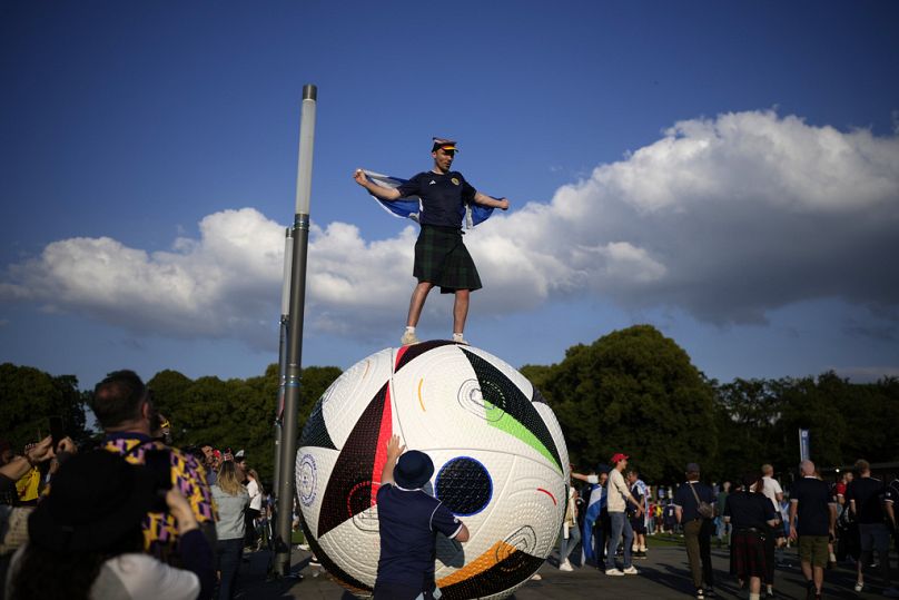 A Scottish fan stands atop of a giant replica ball ahead of a Group A match between Scotland and Switzerland in Cologne, 19 June 2024