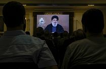 Hezbollah supporters watch a speech given by Hezbollah leader Sayyed Hassan Nasrallah on a screen during a ceremony.