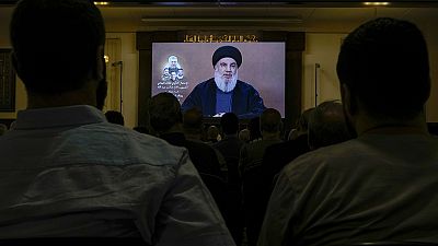 Hezbollah supporters watch a speech given by Hezbollah leader Sayyed Hassan Nasrallah on a screen during a ceremony.