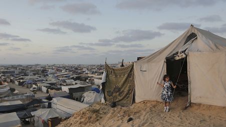 فتاة فلسطينية تقف عند مدخل خيمة عائلتها في مخيم مؤقت للنازحين في خان يونس