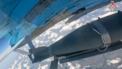 На этом снимке из недатированной видеозаписи, опубликованной Минобороны РФ, видно, как самолёт ВВС России выпускает управляемую бомбу.