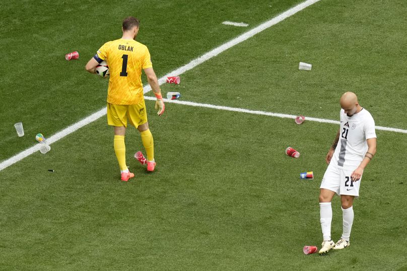 Jogadores da Eslóvenia retiram objetos atirados para o relvado pelos adeptos da Sérvia.