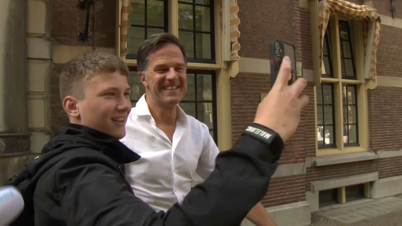 Mark Rutte poses for selfies with teenagers outside his office in The Hague.