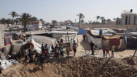 فلسطينيون يتجمعون على حافة حفرة بعد غارة جوية إسرائيلية في منطقة لجأ إليها النازحون في خان يونس جنوب قطاع غزة، الجمعة 21 يونيو