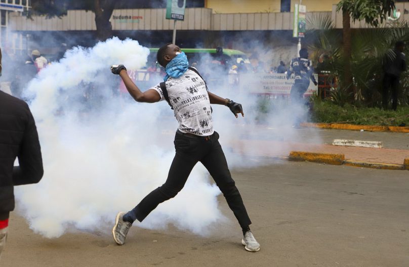 A protesters throws back a teargas canister at police officers during a protest over proposed tax hikes in a finance bill that is due to be tabled in parliament in Nairobi, Ke