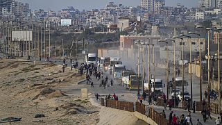 Filistinliler, 18 Mayıs 2024 Cumartesi günü Gazze Şeridi'nin merkezinde, ABD tarafından inşa edilen yeni bir iskeleden getirilen insani yardım yüklü kamyonlara hücum ediyor.