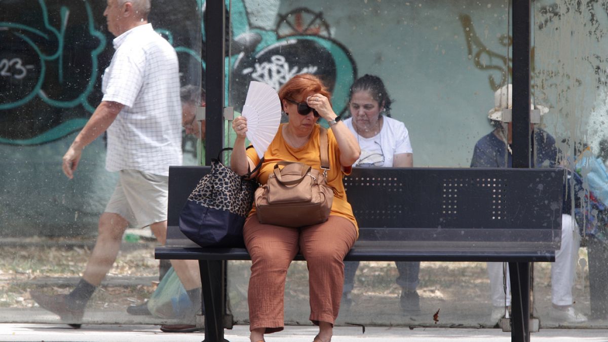 Uma mulher tenta refrescar-se enquanto espera por um autocarro num dia quente em Skopje, na Macedónia do Norte