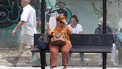Uma mulher tenta refrescar-se enquanto espera por um autocarro num dia quente em Skopje, na Macedónia do Norte