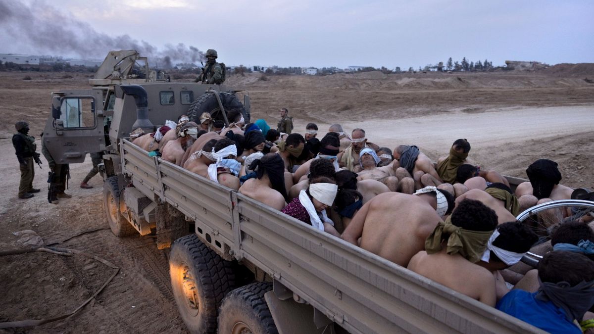 جنود إسرائيليون بجانب شاحنة محملة بأسرى فلسطينيين مقيدين ومعصوبي الأعين في غزة