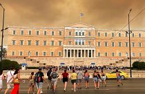 Smoke from wildfires is seen above the Greek parliament building in central Athens, 11 August, after a blaze northeast of the capital forced evacuations in the area.