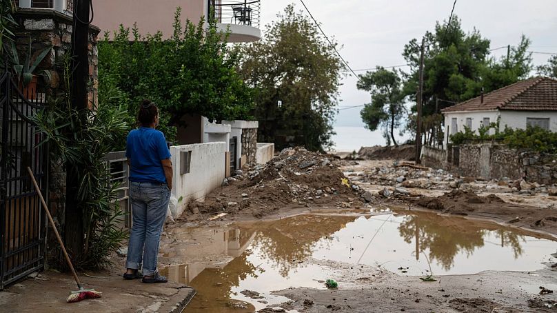 A woman looks on outside her house at the flooded streets in the town of Agria near the city of Volos, Greece, 28 September 2023.