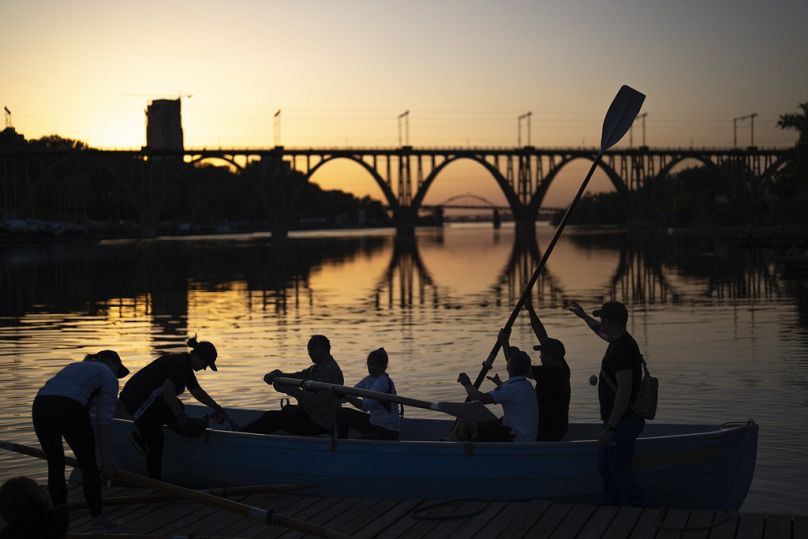 Ukrainians, a few of them displaced from Mariupol during the war, train at rowing on the Dnipro river as the sun sets, in Dnipro, May 2024