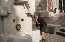 Un uomo si rinfresca in una fontana pubblica a Belgrado, in Serbia, venerdì 21 giugno 2024. 