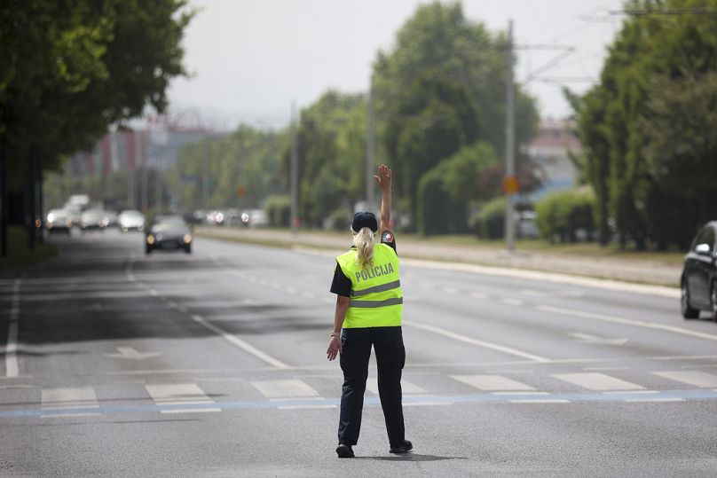 ضابطة شرطة تشير إلى السيارات وهي تحاول السيطرة على حركة المرور أثناء انقطاع التيار الكهربائي في سراييفو، البوسنة، الجمعة، 21 يونيو 2024.