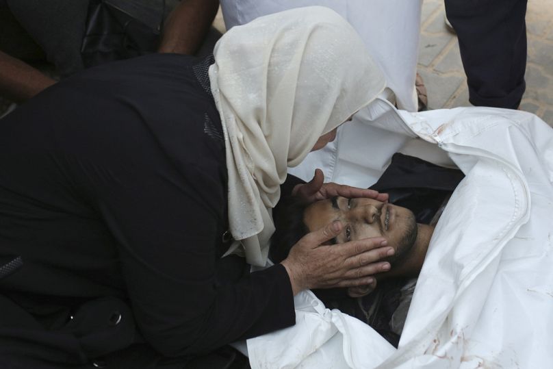 A Palestinian woman takes a last look at a loved one killed by Israeli bombardment, before his burial in Khan Younis, southern Gaza Strip, Friday, June 21, 2024. 