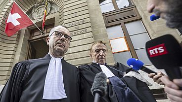 محامو المتهم، نيكولا جاندين، إلى اليسار، وروبرت أسايل، إلى اليمين، يغادران مبنى المحكمة في جنيف، سويسرا، 22 يونيو 2024