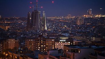 FILE - Buildings and La Sagrada Familia basilica are illuminated at night in Barcelona, Spain, Wednesday, March 18, 2020.