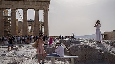 Imagen de varias personas en el espacio turístico de la Acrópolis en Atenas.