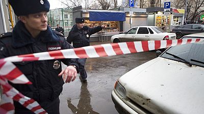 Полицейские устанавливают ленту на месте преступления возле подозрительного автомобиля (на заднем плане) в Москве, Россия, суббота, 28 февраля 2015 года. 
