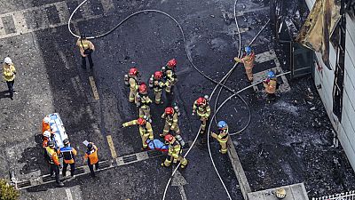Imagen de varios miembros del cuerpo de bomberos trasladando el cadáver de uno de los muertos tras un incendio en una fábrica de baterías de litio en Corea del Sur.