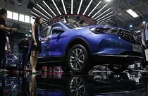 Journalists and visitors look at a Chinese car brand Hanteng X5 EV SUV on display at the China Auto China in Beijing, Thursday, April 26, 2018. 