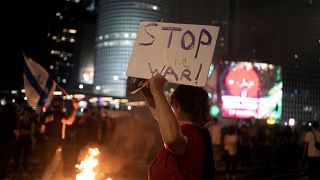 Netanyahu karşıtı bir İsrailli eylemci, elinde "Savaşı Durdur" yazılı bir dövizle, Tel Aviv'de protestoda (23 Haziran 2023)