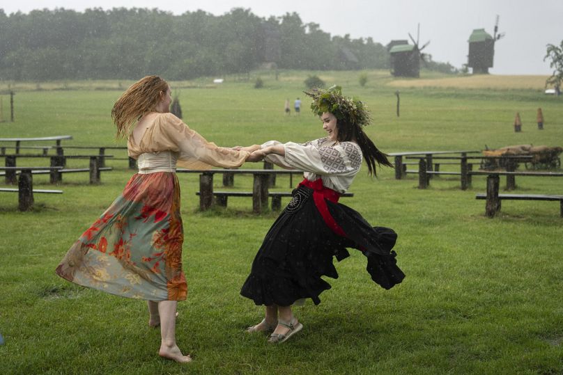 Ukrainische Frauen tanzen bei starkem Regen auf einer traditionellen Mittsommernachtsfeier in der Nähe der ukrainischen Hauptstadt Kiew, Sonntag, 23. Juni 2024. 