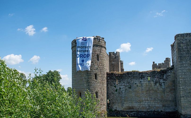 Fossil Free London unfurls a banner at Grade I-listed monument Bodiam Castle in Sussex, England, in protest at owner the National Trust’s links to Barclays.