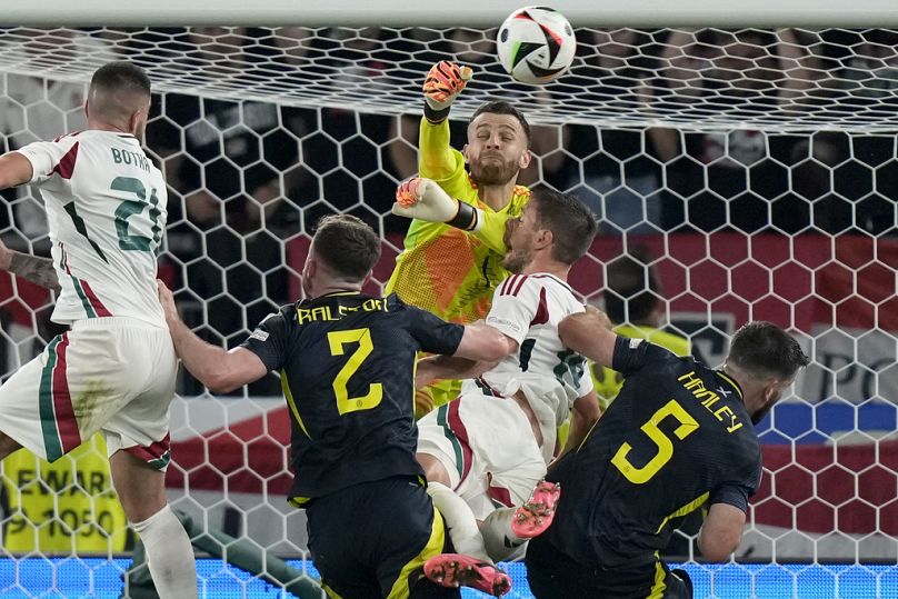 Scotland's goalkeeper Angus Gunn, up, and Hungary's Barnabas Varga, center, collide during a Group A match between Scotland and Hungary at Euro 2024