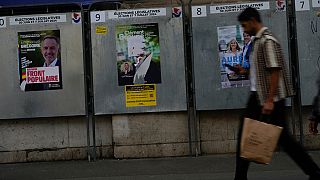 People walk past campaign boards for the upcoming parliamentary elections in Paris, Saturday June 22