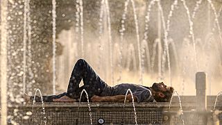 A man cools off by city fountains on a hot evening in Bucharest, Romania, Friday, June 21, 2024.