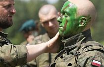 Volunteers in Poland's army learn to apply camouflage face paint during basic training in Nowogrod, 20 June 2024