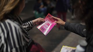 Un voluntario entrega un folleto informativo del Nuevo Frente Popular a una ciudadana en Francia.