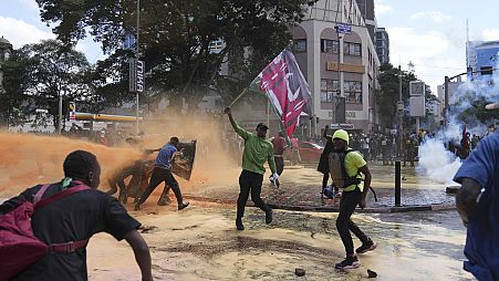 Protesters scatter as Kenya police spray a water canon at them during a protest over proposed tax hikes in a finance bill in downtown Nairobi, Kenya Tuesday, June. 25, 2024. 