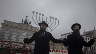 حاخامان يهوديان يرقصان أمام شمعدان حانوكا أمام بوابة براندنبورغ في ساحة بارايزر بلاتز في وسط العاصمة الألمانية برلين