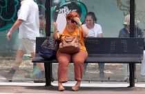 Μια γυναίκα προσπαθεί να δροσιστεί περιμένοντας ένα λεωφορείο μια ζεστή μέρα στα Σκόπια, στη Βόρεια Μακεδονία, στις 20 Ιουνίου 2024. 