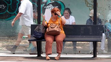 Μια γυναίκα προσπαθεί να δροσιστεί περιμένοντας ένα λεωφορείο μια ζεστή μέρα στα Σκόπια, στη Βόρεια Μακεδονία, στις 20 Ιουνίου 2024. 