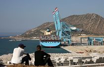 عاملان مغربيان ينظران إلى ميناء طنجة ​​بعد افتتاحه من قبل الملك المغربي محمد السادس في مدينة طنجة الشمالية، الجمعة 27 يوليو 2007