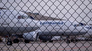 Lufthansa aircrafts are parked behind a fence at the airport in Frankfurt, Germany.