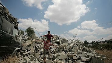 فتية فلسطينيون يقفون على أنقاض منزل هدمه الجيش الإسرائيلي في قرية اللبن الغربية بالضفة الغربية، بالقرب من رام الله.