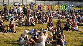 Festival goers sit on a hill at the Glastonbury Festival in Worthy Farm, Somerset, England