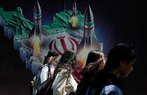 زنان ایرانی از جلوی دیوارنگاره‌ای در تهران عبور می‌کنند