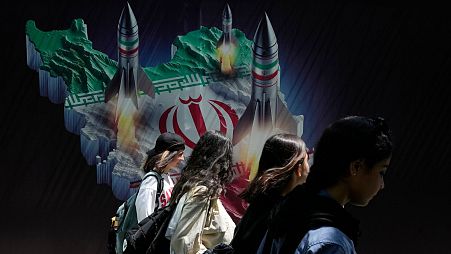 زنان ایرانی از جلوی دیوارنگاره‌ای در تهران عبور می‌کنند