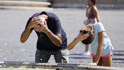 Туристы охлаждаются у фонтана на площади Пьяцца дель Пополо в Риме