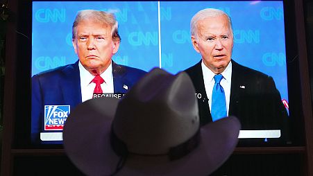 A man wears a cowboy hat as he watches the presidential debate between Joe Biden and Donald Trump in Scottsdale, AZ, 27 June 2024